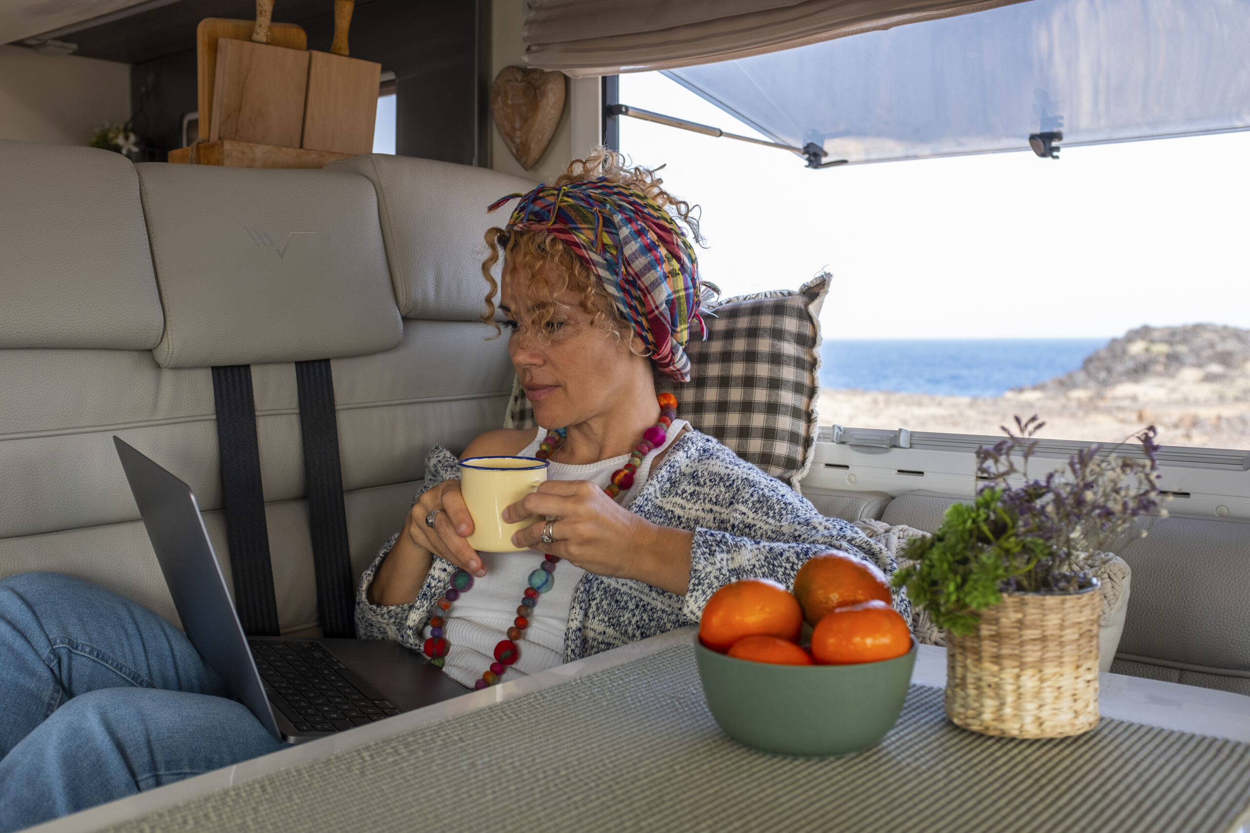 One independent woman laying and working inside a camper van wit One independent woman laying and working inside a camper van with laptop and connection. Free lifestyle and alternative office workstation for modern online worker people. Digital nomad lady activity